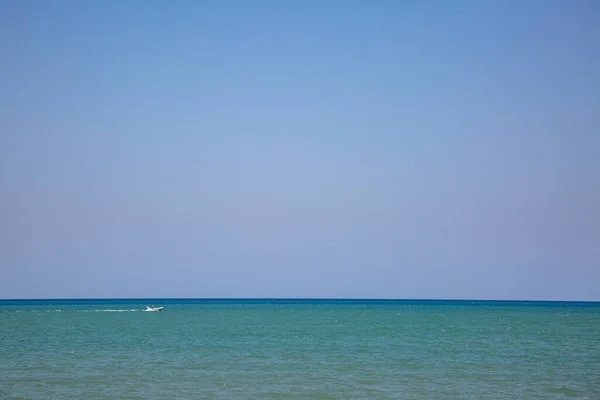 stock image A serene blue sky above turquoise waters of the Adriatic with a tiny white boat in sight