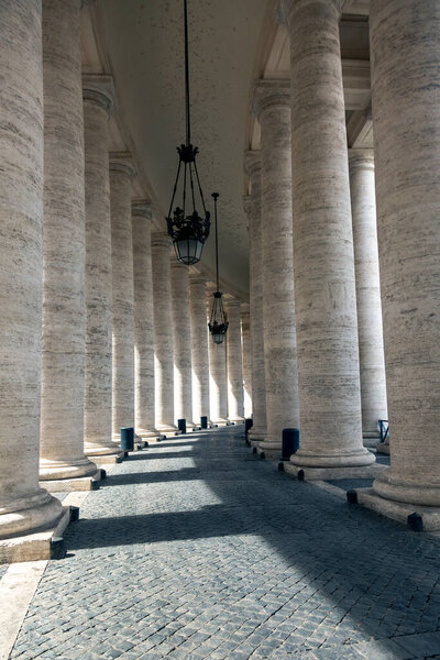 A row of columns with a chandelier hanging from the ceiling