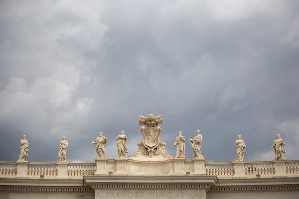 Statues of famous people above the building with columns in the Vatican, Rome, Italy