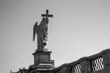 Heykellerin siyah-beyaz görüntüsü üzerinde haç olan köprüdeki bir melek. Roma, İtalya