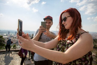 Güneşli bir günde arka planda şehrin manzarasını çeken bir çift selfie çeker..
