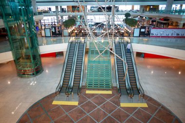 Pürüzsüz yürüyen merdivenleri ve sanatsal metal heykel süsü olan modern havaalanı terminali. Çağdaş tasarımı gezgin rahatlığı için fonksiyonel elementlerle harmanlayan geniş ulaşım merkezi.