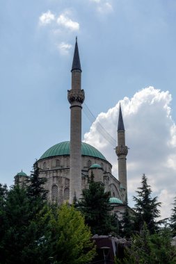 İkiz minareler, şehrin kalbindeki inancın sembolü olan gökyüzünü deliyor. Görkemli bir cami, kabarık bulutların altında dimdik ayakta duruyor..