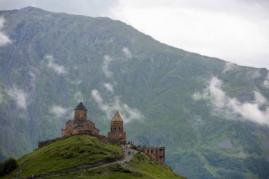 Gürcistan 'daki Stepantsminda köyü yakınlarındaki Kazbek Dağı' nın altında antik bir Gergeti Trinity Kilisesi ile nefes kesici bir sıradağ manzarası.