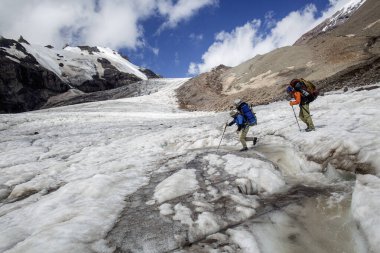 Dağcılar, uçsuz bucaksız, dramatik dağ manzarasıyla çevrili Kazbek 'in karlı sırtlarında yokuş yukarı yürüyorlar. Gergeti Buzulu