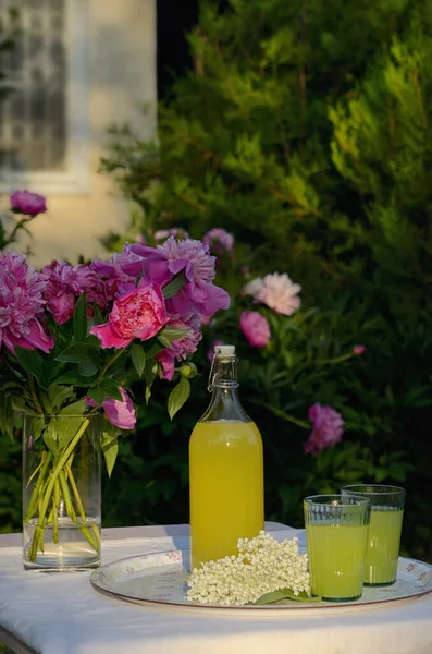 テーブルの上のエルダーベリーシロップから作られた自家製レモネードのボトルとグラス ストック写真