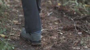 Çamurlu ormanda yürüyüş botlarıyla yürüyen biri. Mavi çizmeler ve yürüyüş pantolonu patikada.