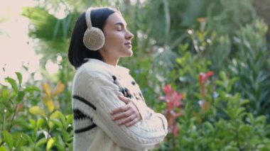 Soğuk için kulaklık takan bir kız derin derin nefes alır ve gözlerini kapatır. Rahatlamış, ormanda gözlerini kapatıyor ve açıyor. Çok sakin, rahatlatıcı ve huzurlu..