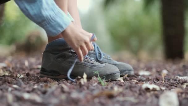 女孩把蓝色远足靴的鞋带捆起来 在田野和山底 有棕色的森林叶子 — 图库视频影像