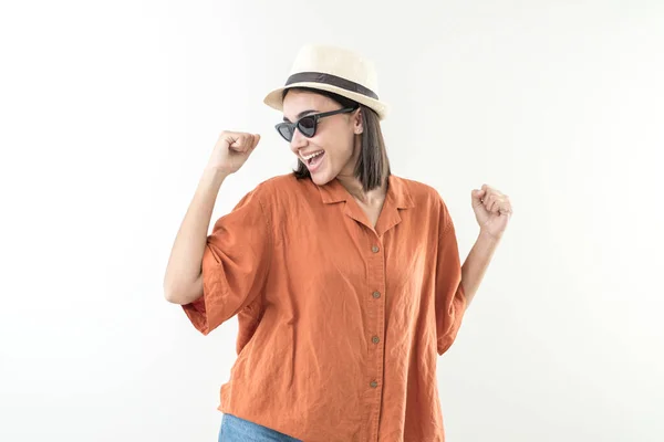 Stock image Happy young girl with cap and sunglasses raises her fists. She is happy with her dark glasses and orange shirt.