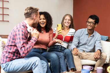 Kampüs salonunda eğlenen genç üniversite öğrencileri müzik dinliyor ve cep telefonlarıyla oynuyorlar - kahvaltıda Z jeneratörleri ve kızlarla sosyal ağ konsepti