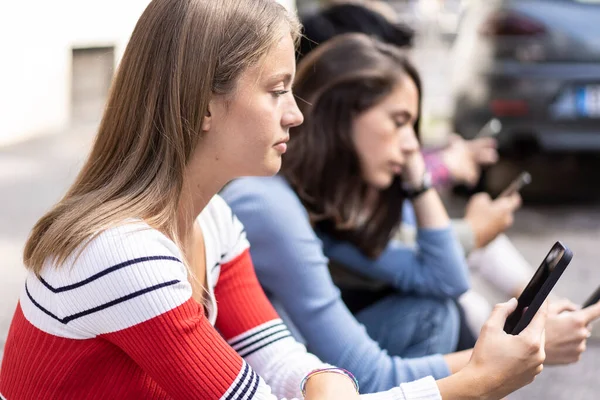 坐在大学校园后院里用智能手机的无聊朋友小组 沉迷于手机的年轻人 总是连接着学生的科技悲伤生活理念 对比过滤器 — 图库照片