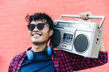 Genç Asyalı hippi yaz tatillerinde kulaklıkla ve klasik müzik kutusuyla müzik dinleyerek eğleniyor.