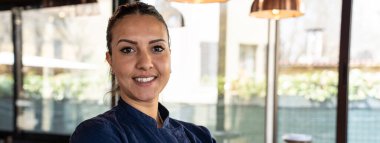 Restoranda kameraya gülümseyen genç Afrikalı aşçı kadınla yatay pankart ya da başlık