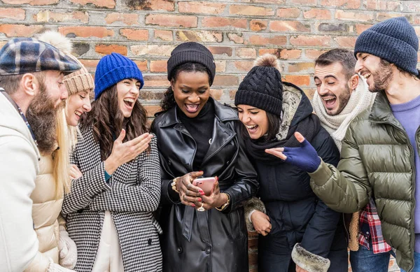 多文化的都市朋友们穿着温暖时尚的衣服在手机上玩乐 快乐的多文化朋友们在智能手机上一起分享时光 温暖的过滤器 — 图库照片