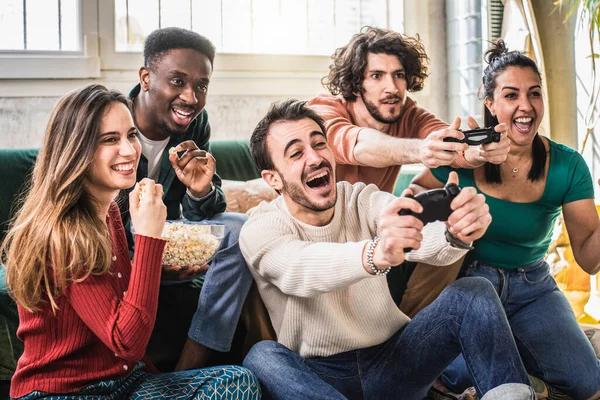 幸せな多民族の友人がソファに座ってビデオゲームをしている 現代の技術ビデオゲームで楽しんでいる陽気な世代のZグループ ホビーと技術の概念 — ストック写真