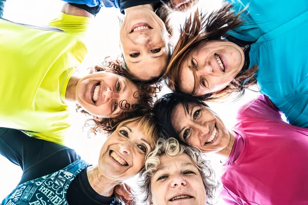 stock image Multigenerational female friends embrace in a circle and looking down at camera after sport workout outdoor - Happy multi generational women having fun together at city park - Bright filter