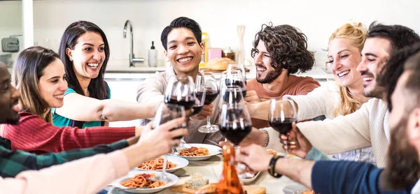 友人はトマトとスパゲティを食べながら夕食で赤ワイングラスを味わいます イタリアのパスタと赤ワインと一緒に夕食を楽しんでいる多民族の男 バナーまたは明るいフィルター付きヘッダー — ストック写真