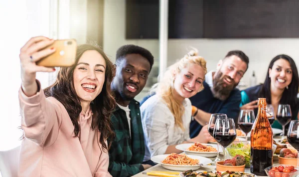 多民族の男性と女性が自宅のキッチンで昼食のために自撮り トマトソースとおいしいイタリアのスパゲティを食べながら アパートで一緒に楽しんでいる若い友人 明るいフィルター ストック写真