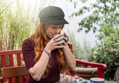 Caffetteria Bar Garden 'da latte ya da Amerikan kahvesi içen dalgın genç bir kadın.