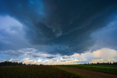 Huysuz, karanlık bulutlar canlı mavi gökyüzünü dolduruyor. Aşağıdaki manzaranın üzerinde yaklaşan fırtınayı işaret ediyor.