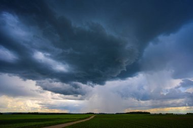 Huysuz, karanlık bulutlar canlı mavi gökyüzünü dolduruyor. Aşağıdaki manzaranın üzerinde yaklaşan fırtınayı işaret ediyor.