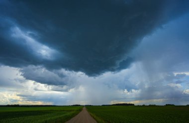 Huysuz, karanlık bulutlar canlı mavi gökyüzünü dolduruyor. Aşağıdaki manzaranın üzerinde yaklaşan fırtınayı işaret ediyor.