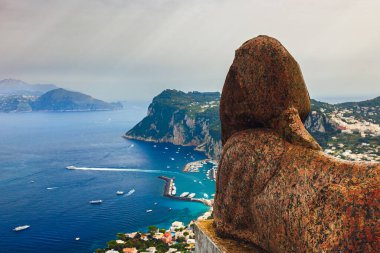 İtalya 'nın Capri Adası' ndaki tarihi bir heykelden nefes kesen sakin bir sahil manzarası.