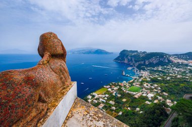İtalya 'nın Capri Adası' ndaki tarihi bir heykelden nefes kesen sakin bir sahil manzarası.