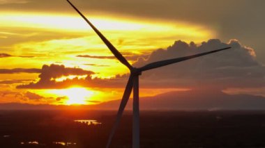 Gün batımında rüzgar türbinlerinin etrafındaki hava gözlem dronu çiftliği, telefoto görüntüsü, yenilenebilir elektrik enerjisi.