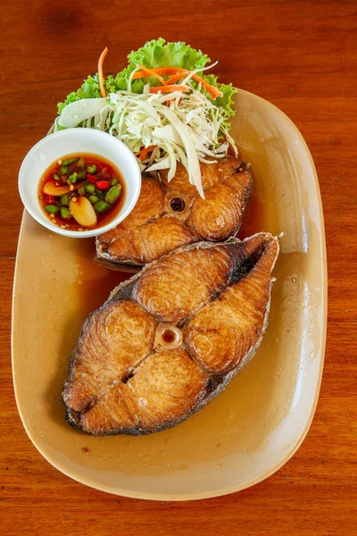 带有木桌背景的鱼酱汁的深炸鲭鱼 泰式海鲜 图库图片