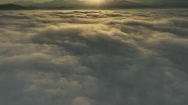 Hava görüntüsü öne doğru uçar ve sis denizinde gün doğumunu gözler önüne serer.