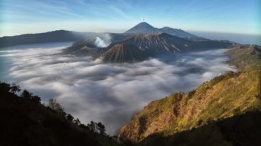 Hava aracı görüntüsü, Bromo volkanını arka planda, Java, Endonezya 'da ortaya çıkarmak için tepenin üzerinden uçuyor.