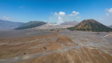 Hiperlapse hava aracı görüntüsü Bromo Dağı etkin yanardağına doğru uçuyor. Aşağıda turist arabası, Java, Endonezya 