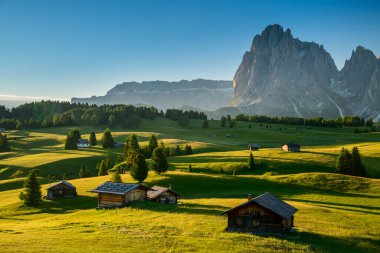 Seiser Alm 'da Chalets, arka planda Langkofel Dağı ile yüksek irtifa çayırı, gündoğumunda Dolomitler, Güney Tyrol, İtalya
