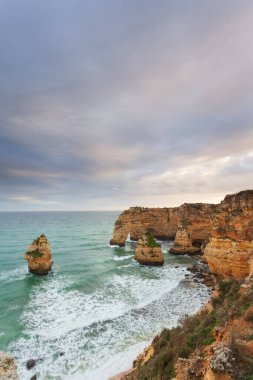 Gün batımında Algarve sahilinde manzara. Portekiz 'in güneyindeki plaj turistler için en iyi tatil yeridir. Uçurumlarda mağaraları olan deniz manzarası