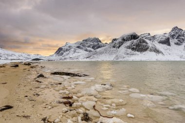 Norveç 'teki Lofoten Adaları ve gün batımındaki güzel kış manzaraları. Karla kaplı plajdaki Idyllic manzarası. Kuzey Kutbu 'ndaki turistik bölge. İskandinav seyahat hedefi.