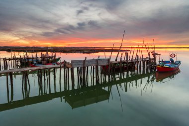 Amazing sunset on the palatial pier of Carrasqueira, Alentejo, Portugal. Wooden artisanal fishing port, with traditional boats on the river Sado. fineart color horizontal photography. clipart