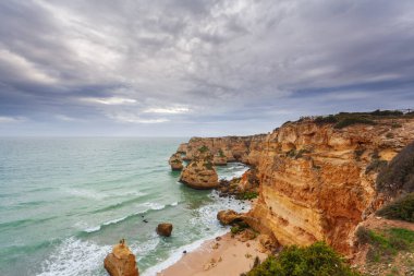 Gün batımında Algarve sahilinde manzara. Portekiz 'in güneyindeki plaj turistler için en iyi tatil yeridir. Uçurumlarda mağaraları olan deniz manzarası