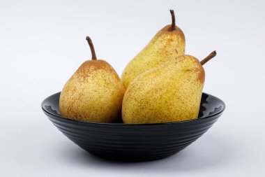 Siyah bir tabakta üç armut.