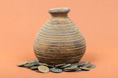 Antik Roma sikkeleriyle çevrili Rustik kil kavanozu.