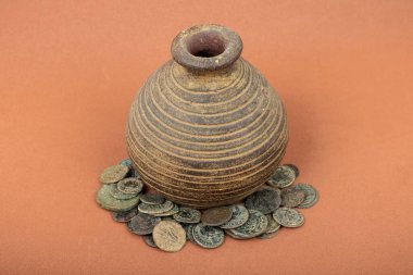 Antik Roma sikkeleriyle çevrili Rustik kil kavanozu.