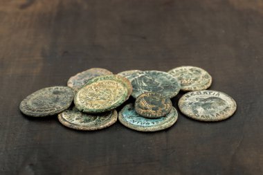 Ancient Roman coins with patina scattered on a wooden surface. clipart