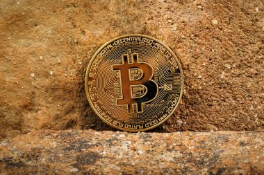 Bitcoin şifreleme madeni para engebeli bir taş zemin üzerinde sergilenir.