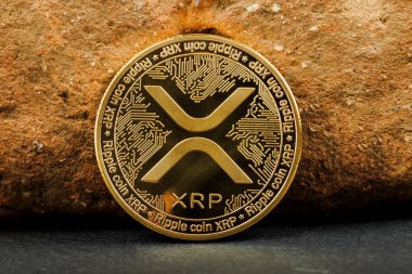 Dalgalanan XRP şifreleme madeni para ile desenli bir kaya zemin üzerine yerleştirilmiş altın ayrıntılar.