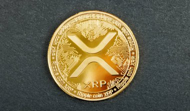 Dijital para birimini sembolize eden, koyu desenli bir yüzey üzerindeki altın XRP dalgalı kripto para birimini kapat.