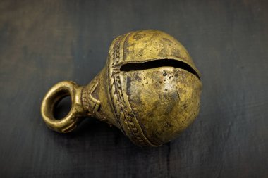 Karmaşık oymaları olan antika pirinç çan ve koyu dokulu arka planda eskimiş ezme..