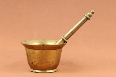 Antique brass mortar and pestle on a warm-toned background clipart