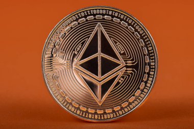 Turuncu arka planda metalik kaplamalı Ethereum kripto para.
