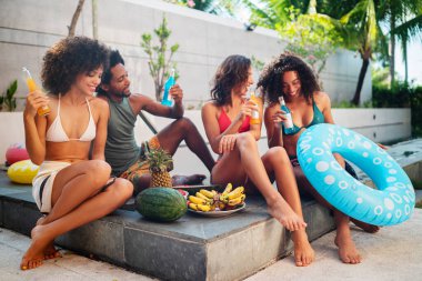 Bir grup mutlu arkadaş yüzme havuzunda eğleniyor. Genç Afro-Amerikan kadınları kokteyl içiyor..